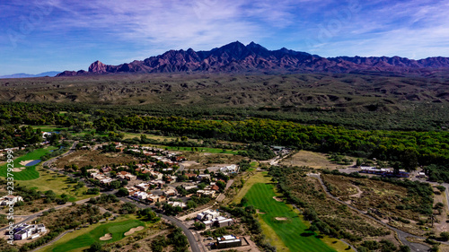 Aerial, drone view of Tubac, Arizona with blue sky, green flora including palo verde trees, purple mountains