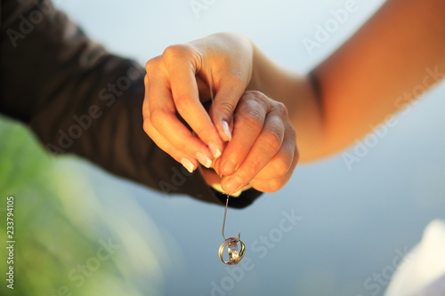Wedding couple hold fishing-hook and wedding ring
 photo