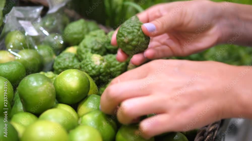 Closeup Of Hand Choosing Between Lime And Bergamot In Supermarket. Closeup Of Hand Choosing Between Lime And Bergamot In Supermarket.