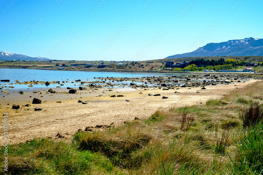 Beach of Puerto Natales with rocks, sand and grass, Patagonia, Chile.