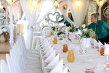 Kelnerka dekoruje stół w restauracji nakryty białym obrusem, ślub, wesele. 