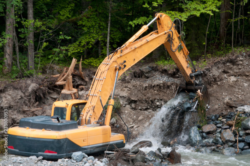 Excavator strengthens the bed of a mountain river.