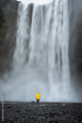 Wearing a Yellow raincoat under a powerful waterfall 