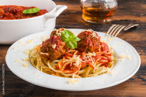 Pasta and meatballs with tomato sauce, white casserole and plate on wooden rustic table