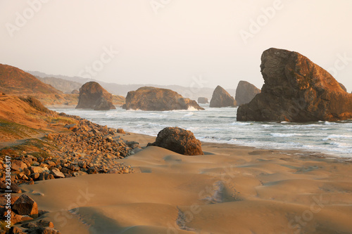 View of the sandy beach and rocks during sunset in the Pacific Ocean