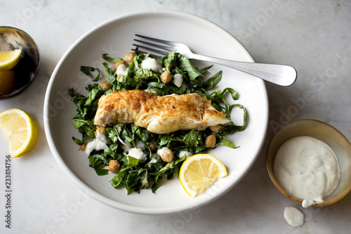 Close up of fried halibut fish with hen salad served on plate