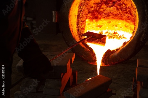 Workers pouring molten metal from flasks into moulds