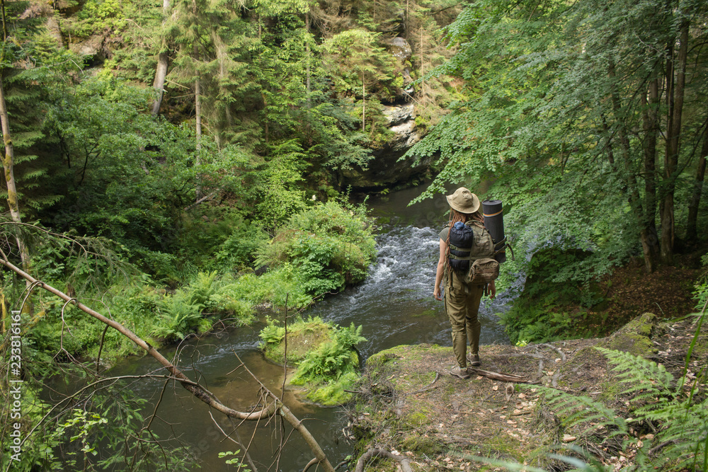 Young woman hiker posing near the river in bohemian switzerland national park, female traveler in mountains of czech republic Young woman hiker posing near the river in bohemian switzerland national park, female traveler in mountains of czech republic