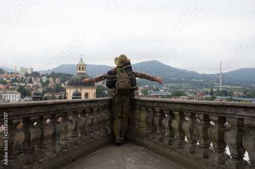 Female traveler stands on the balcony of the castle with old euro city and mountains view  © serejkakovalev