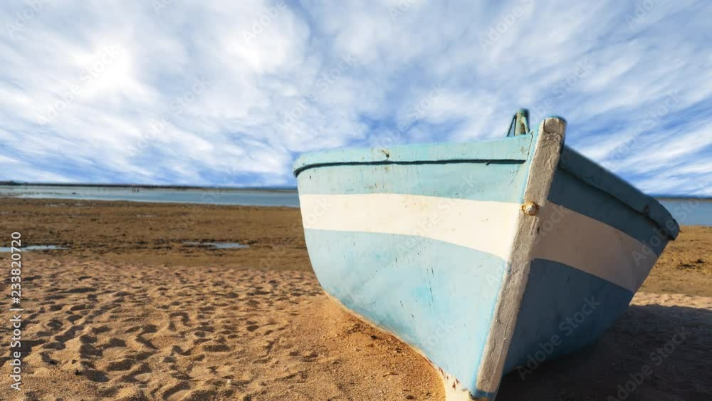 Time lapse of blue fishing boat lie down on a tropical beach with clouds background at beautiful day with calm feeling. Time lapse of blue fishing boat lie down on a tropical beach with clouds background at beautiful day with calm feeling.