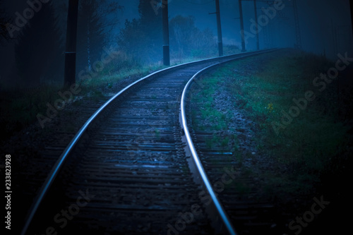 The railroad tracks are curved and stretched to the foreground, covered with a thick fog
