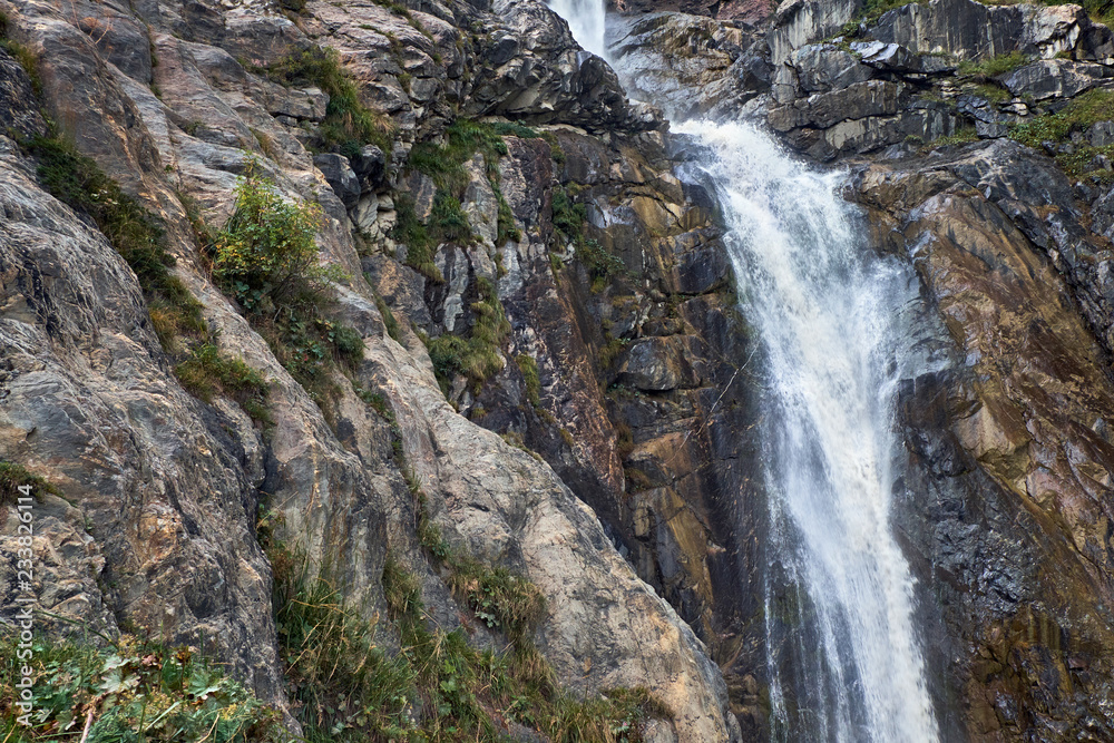 Small glacier icy waterfall in rocky mountains