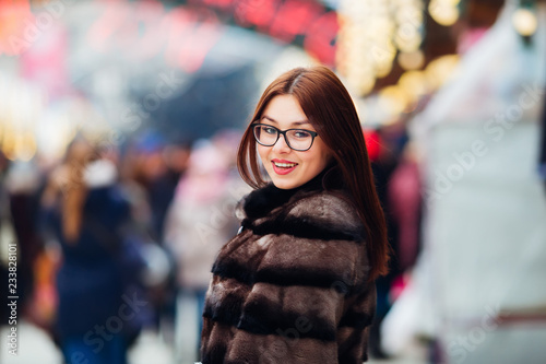 Wallpaper Mural A pretty girl in a fur coat looks at the camera lens and wants to say something on the background of the fair Torontodigital.ca