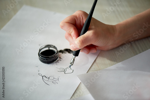 A woman's hand writes with ink, a fountain pen. Writing. The creative process of creating a work