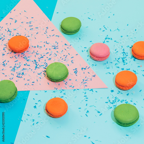 Chaotic heap of colorful almond macaroons or cookies on pink and blue background with confetti. sharp shadows