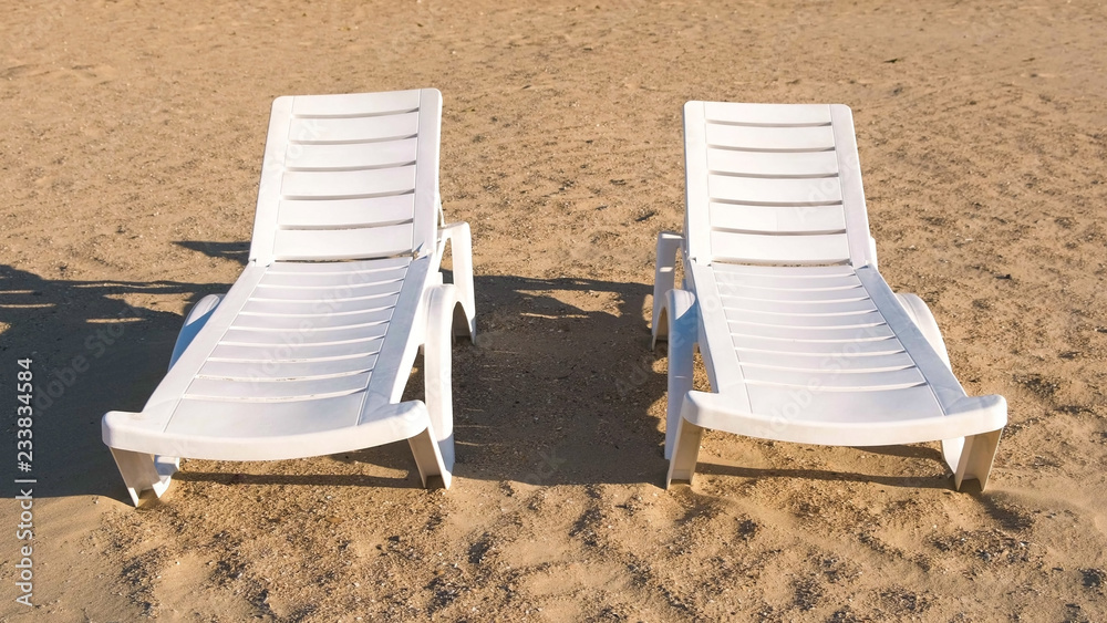 Two sunlongers on the sand beach in summer. Two sunlongers on the sand beach in summer.