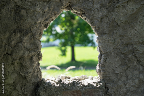 stone background with window and view of blurred green tree.