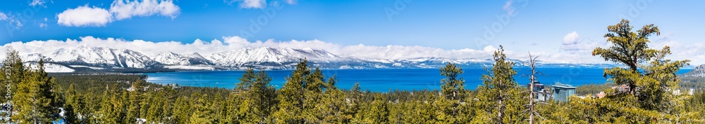 Panoramic view towards Lake Tahoe on a sunny clear day; the snow covered Sierra mountains in the background; evergreen forests in the foreground Panoramic view towards Lake Tahoe on a sunny clear day; the snow covered Sierra mountains in the background; evergreen forests in the foreground