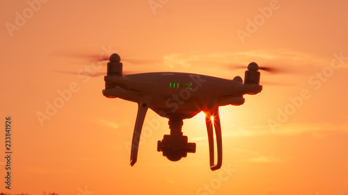 CLOSE UP LENS FLARE SILHOUETTE Filming drone flying over setting sun