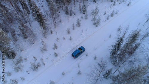 AERIAL Car driving through slippery bend on snowy road in wintry forest, Lapland