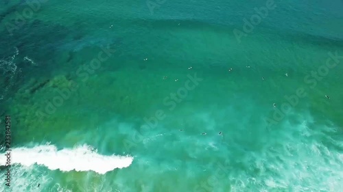 Surfers sitting on board while set of waves are coming zoom in zoom out aerial shot. photo