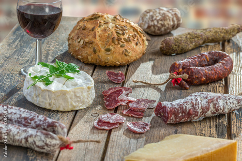 French Snacks with wine - various types of cheeses, bread , dry saussages, charcuterie, red vine on a gray background. Top view. Food background photo