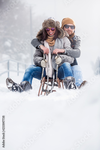 Beautiful couple with sled outdoors in snow