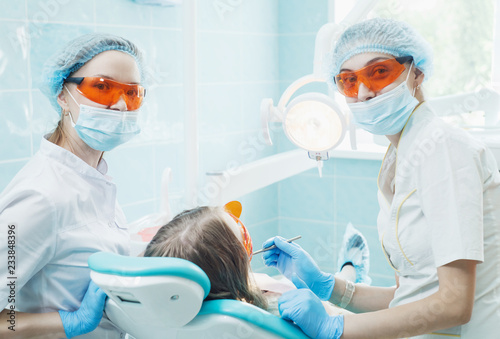 Girl patient with dentist and assistant in a dental treatment