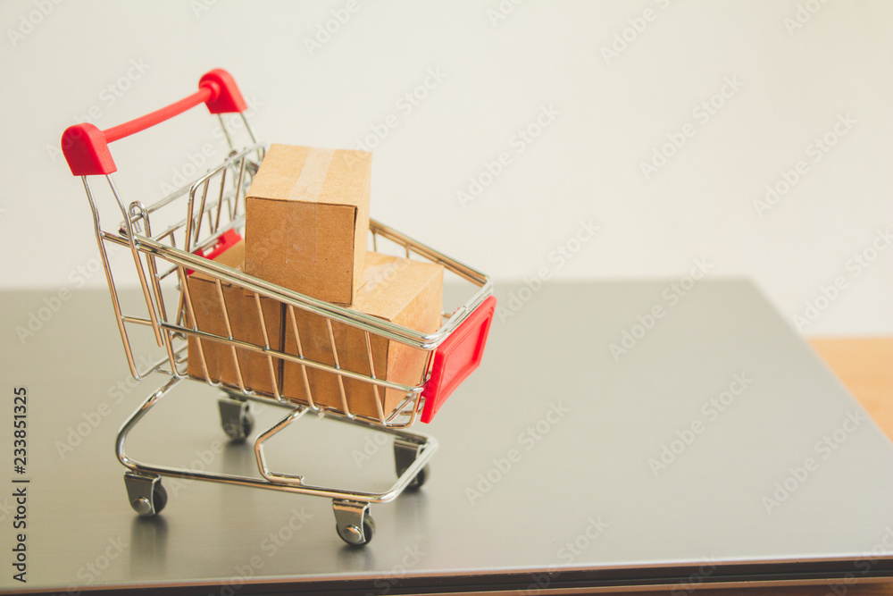 Miniature shopping cart with parcel or paper cartons in trolley on laptop,E-commerce concept.