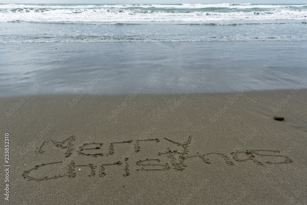 Merry Christmas written in the sand with wet sand behind Merry Christmas written in the sand with wet sand behind