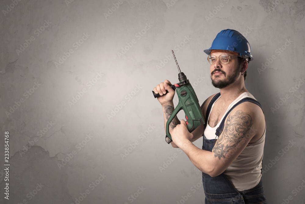 Craftsman standing in front of an empty wall with tool in his hand.