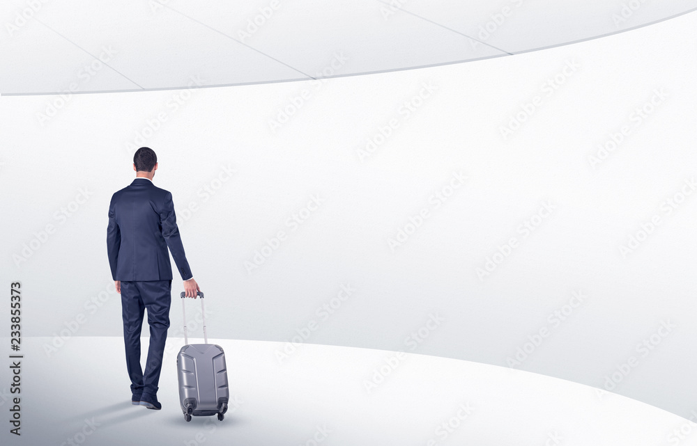 Businessman with back walking in a white waiting room with empty walls around
Businessman with back walking in a white waiting room with empty walls around