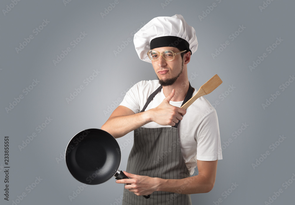 Young bearded cook portrait with kitchen tools and empty wallpaper
Young bearded cook portrait with kitchen tools and empty wallpaper