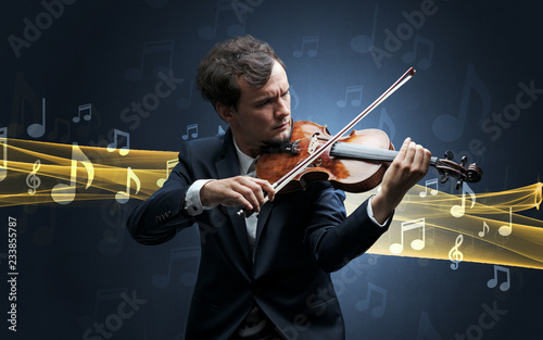 Young male musician playing on his violin with musical notes around photo