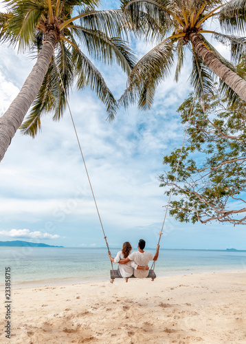 Young couple swinging on a swing on paradise tropical beach, honeymoon, vacation, travel concept photo