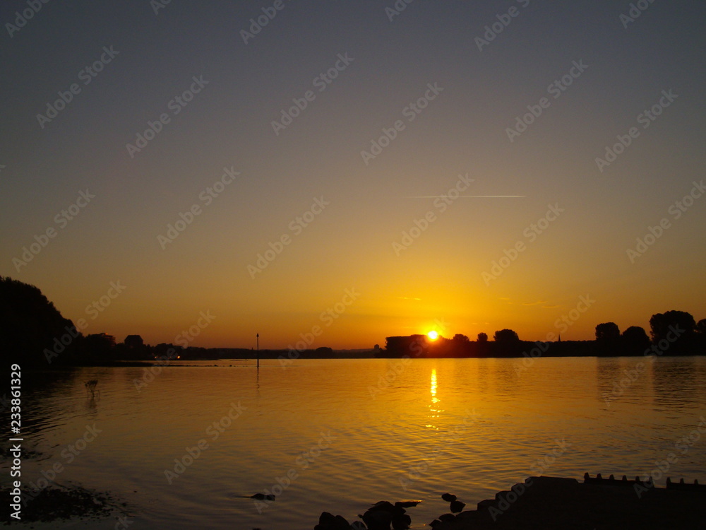 Sonnenaufgang / Sonnenuntergang über dem Fluss (Rhein)