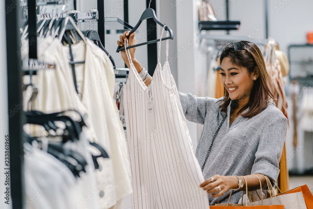Happy Asian woman choosing clothes in shop store with happy action at department center
