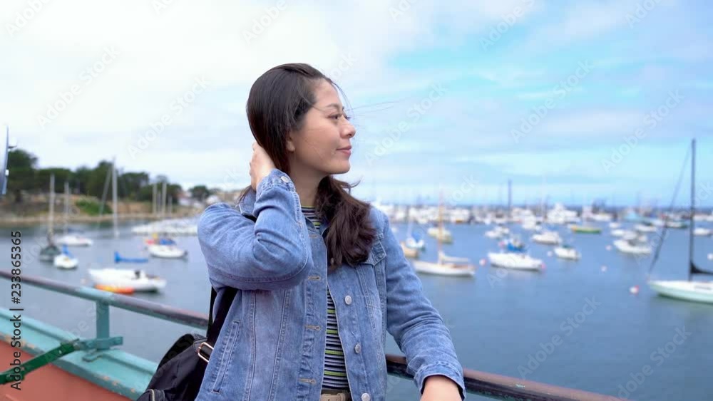 young female traveler enjoy the beauty of?the ocean. travel in spring wind blowing and beautiful lady flicks her long black hair. many boats on the sea in the background with old fisherman on it. young female traveler enjoy the beauty of?the ocean. travel in spring wind blowing and beautiful lady flicks her long black hair. many boats on the sea in the background with old fisherman on it.