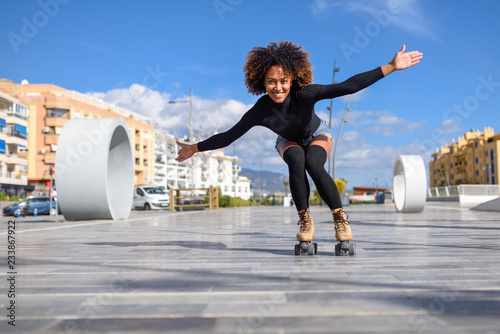 Black woman on roller skates riding outdoors on urban street