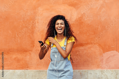 Black woman laughing and listening to music with earphones. photo