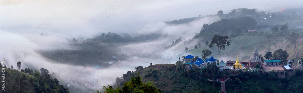 A village and pagoda surrounded by mountains with foggy morning time and orange sky, beautiful landscape