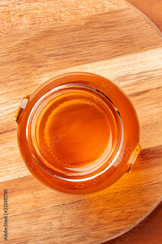 A vibrant jar of organic honey, shot from the top on a rustic wooden background with copy space