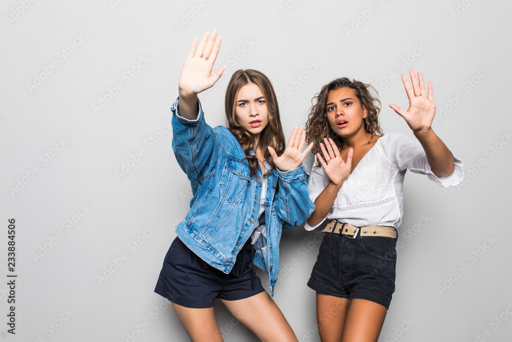 Fototapeta premium Two young girls mixed race making stop sign isolated on gray background
