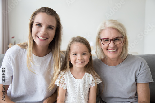 Portrait of three 3 generations family happy old grandmother, smiling young mother and cute preschool child girl looking at camera, kid daughter, mother and aged grandma posing together headshot