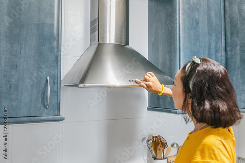 Fotografie Woman turn on exhaust ventilation in the kitchen