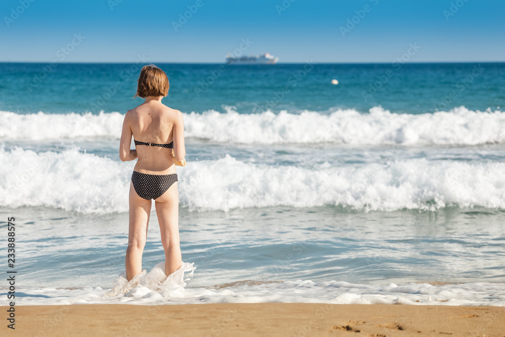 Young woman tourist in swimsuit having fun in wavy waters of Mediterranean sea, storm weather at the sea concept