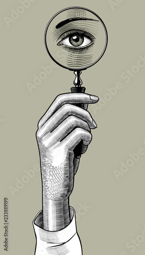 Woman's hand holding a magnifying glass with eye inside
