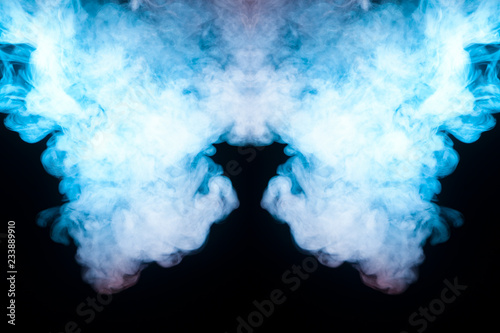 Background of blue wavy smoke in the shape of a jaw closeup on a black isolated ground. Abstract pattern of blue color from steam from vape.