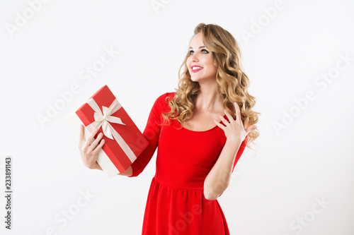 Excited cute girl in red dress holding present box.