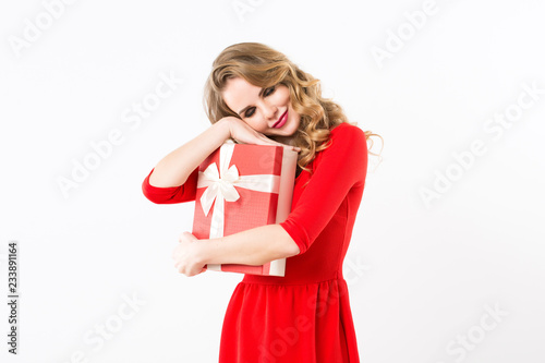 Beautiful cheerful woman in red dress with a gift over white background.